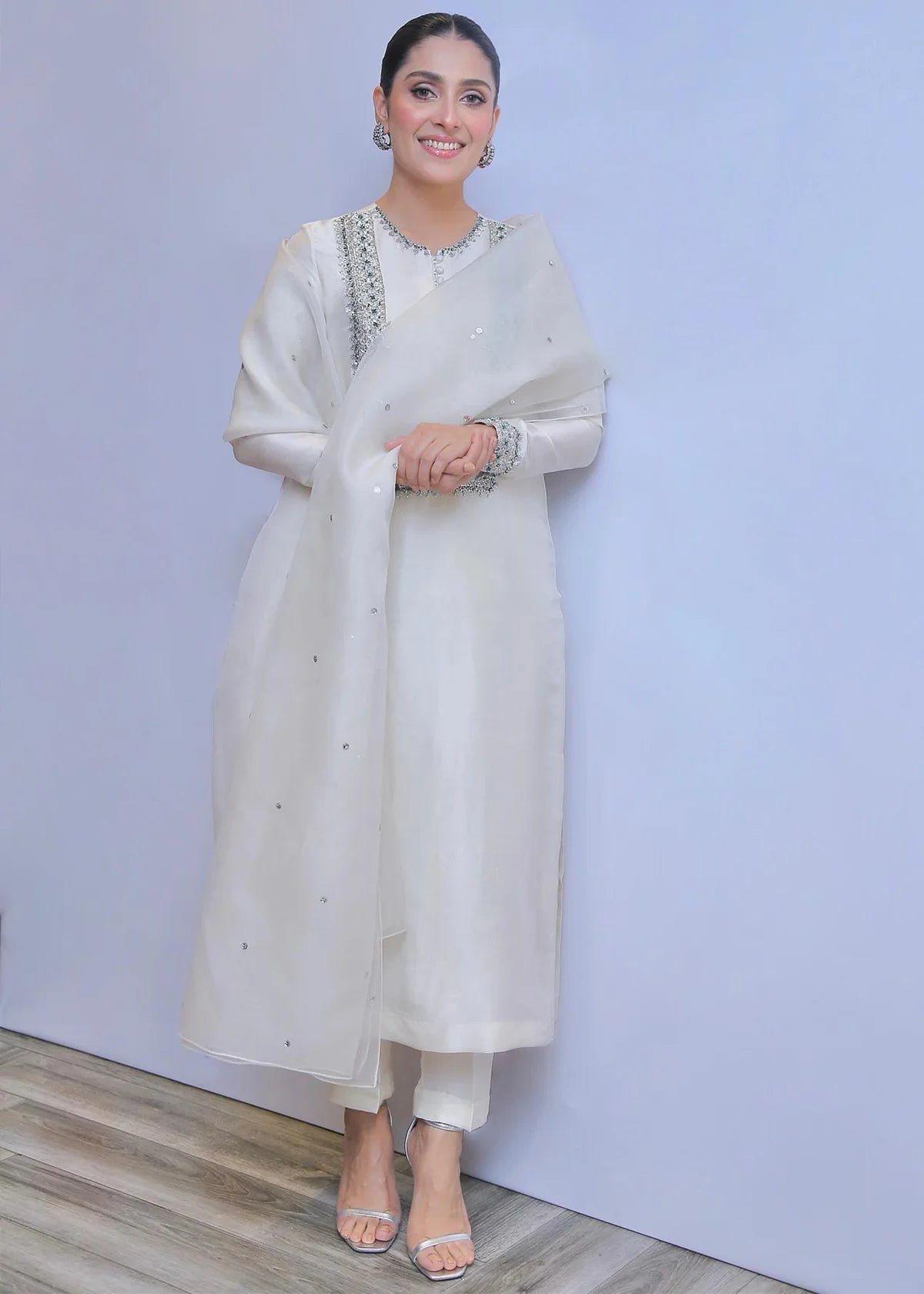 Aiza khan in a white traditional outfit with a plain background