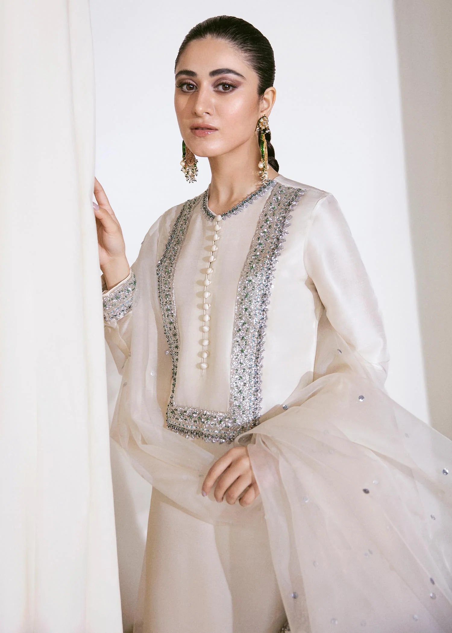 Woman wearing a traditional outfit with intricate designs in a neutral setting