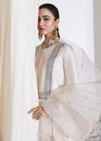 Woman in a white and silver traditional outfit with intricate detailing.