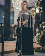 Woman wearing black velvet gown with silver fringe embellished cape