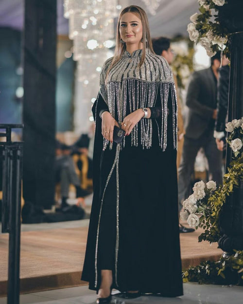 Woman wearing black velvet gown with silver fringe embellished cape